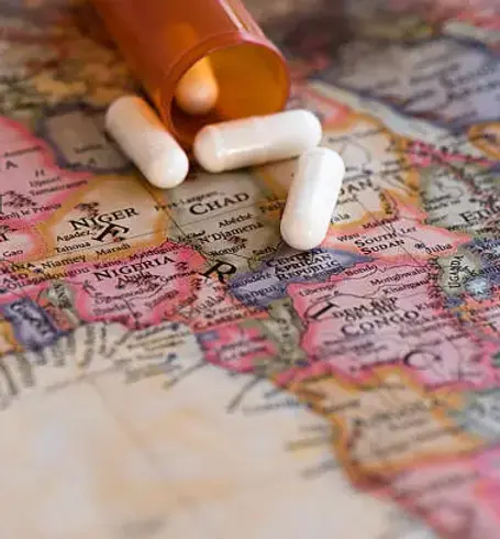 "Close-up of a map of Africa with white capsules spilling from a brown pill bottle, highlighting countries like Nigeria, Chad