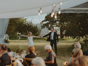 A couple joyfully entering their tented farm wedding reception in Central Alberta