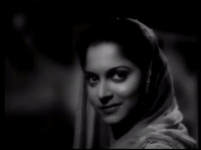 Waheeda Rehman, smiling slightly in a dimly lit setting. Her expression is serene and thoughtful.