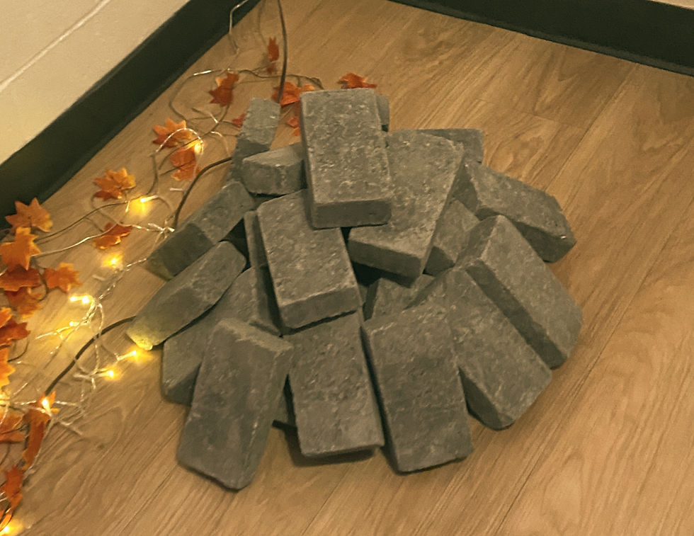 Grey bricks stacked on a wooden floor, surrounded by orange leaves and warm string lights, creating an autumnal and cozy atmosphere.