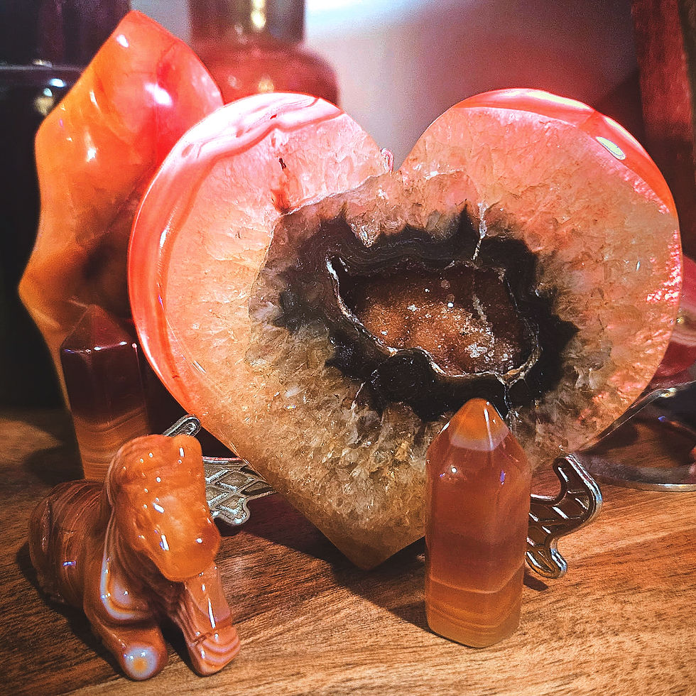 Heart-shaped geode with a dark center, flanked by orange crystal towers and an animal figurine on a wooden surface, under warm light.