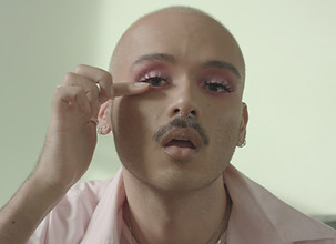 Man with makeup fixing his eyelashes