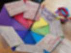 Rainbow umbrella with cardboard signs saying hands off school funding and hands off trans youth.