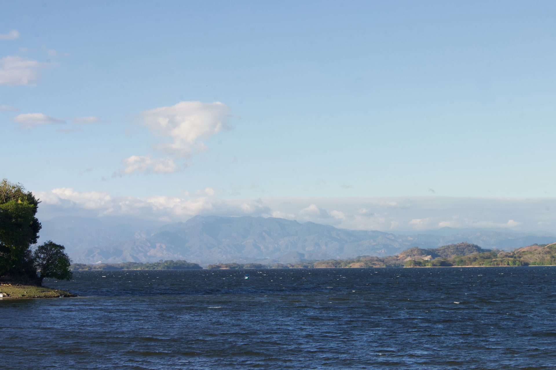 dark water in the foreground and cloud shrouded mountains in the background