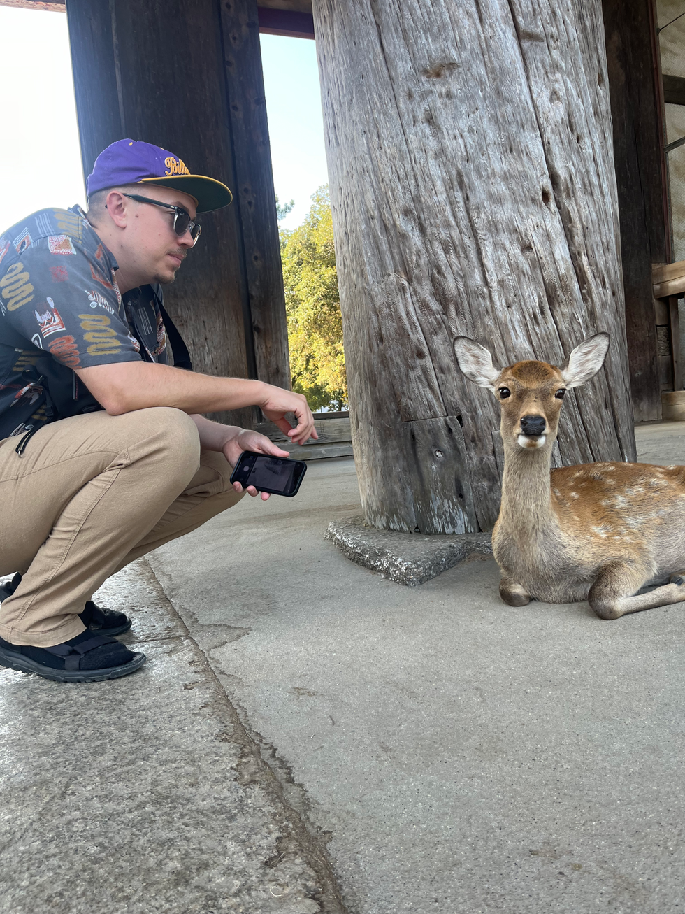 man chroching next to deer 