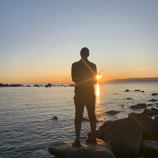 man standing in the sea as the sunsets