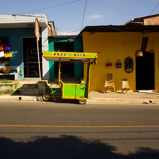 A green and yellow bike drawn cart sits in the road, the street is peaceful