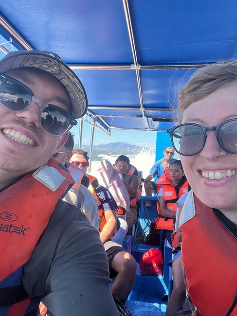Two people taking a selfie together on the boat, everyone in the background is soaked with water, 