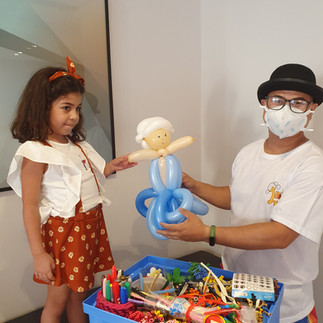 recreador entregando escultura em balões a uma criança