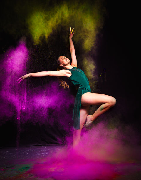 Studio image of a teenage dancer throwing color powder