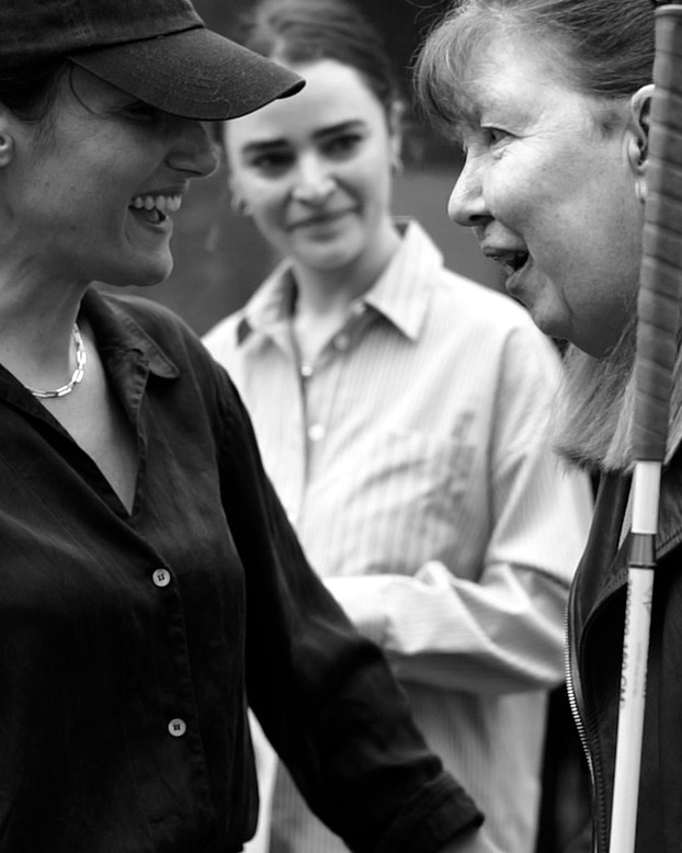 A black and white image of Hair&Care's founder, Anna Cofone welcoming an attendee to the workshop