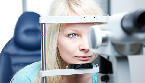 Woman sitting at optometry equipment for eye exam