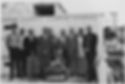A row of men stand in front of a crypt.