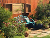 Blue bench with dragonfly pillow in front of the garden fence window