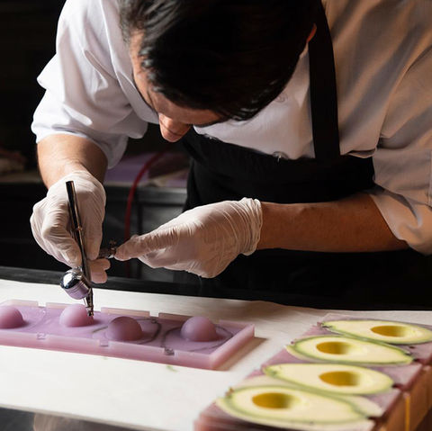 Chef airbrushing plated avocado dessert