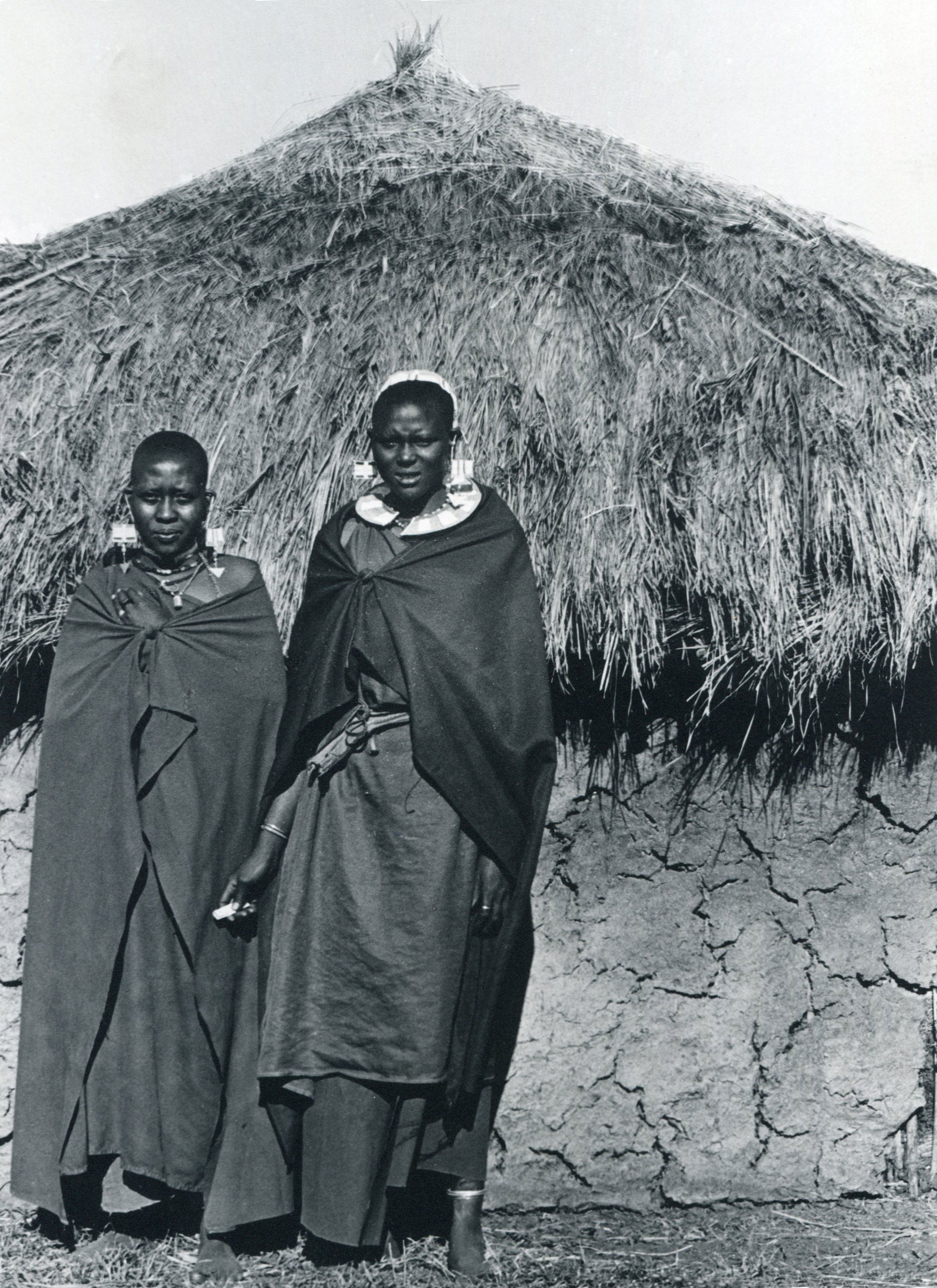 Two women stand near a hut