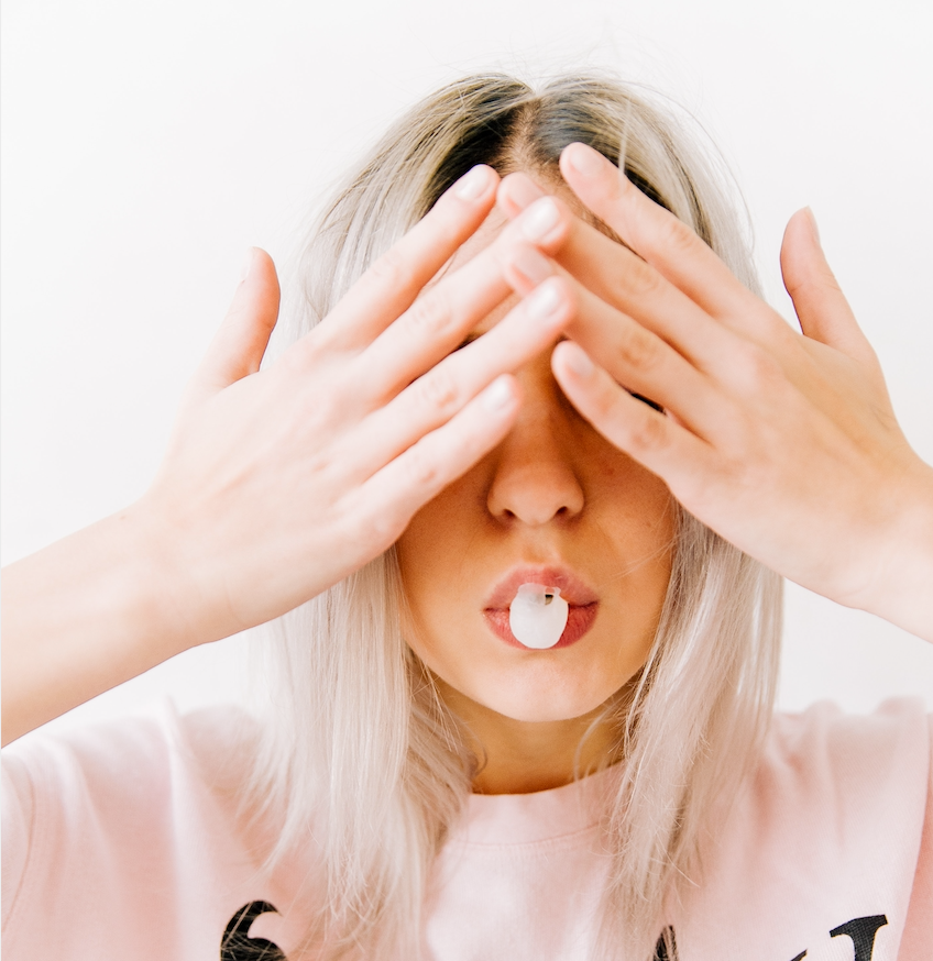 Woman hiding face and blowing a bubble
