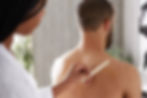 Women applying waxing on men's shoulders