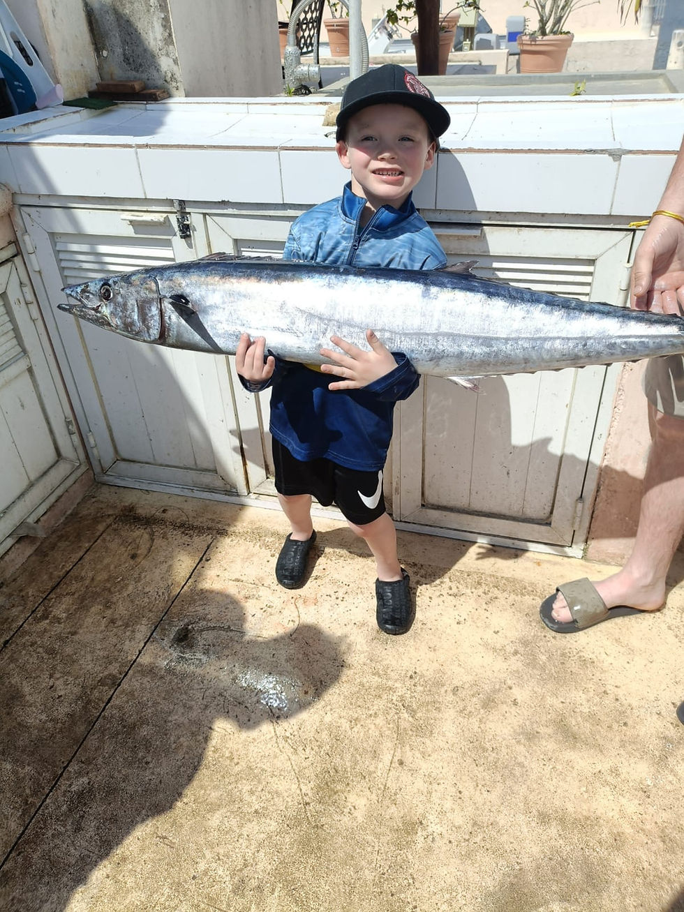 Kid holding large wahoo caught on a family fishing charter in Cozumel Mexico.