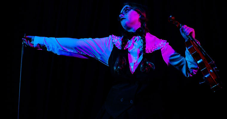A circus performer playing their violin for the audience