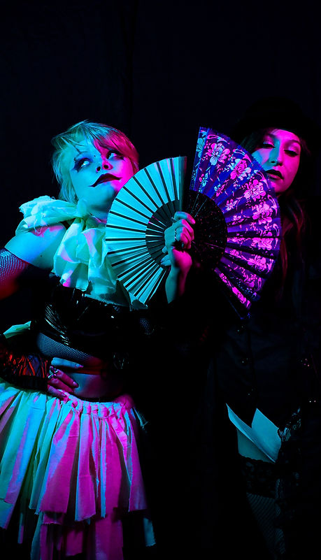 A clown and the magician posing with contrasting fans