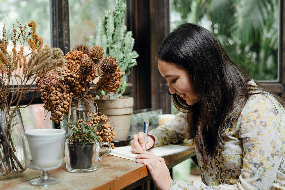 a young woman smiling as she writes in her journal