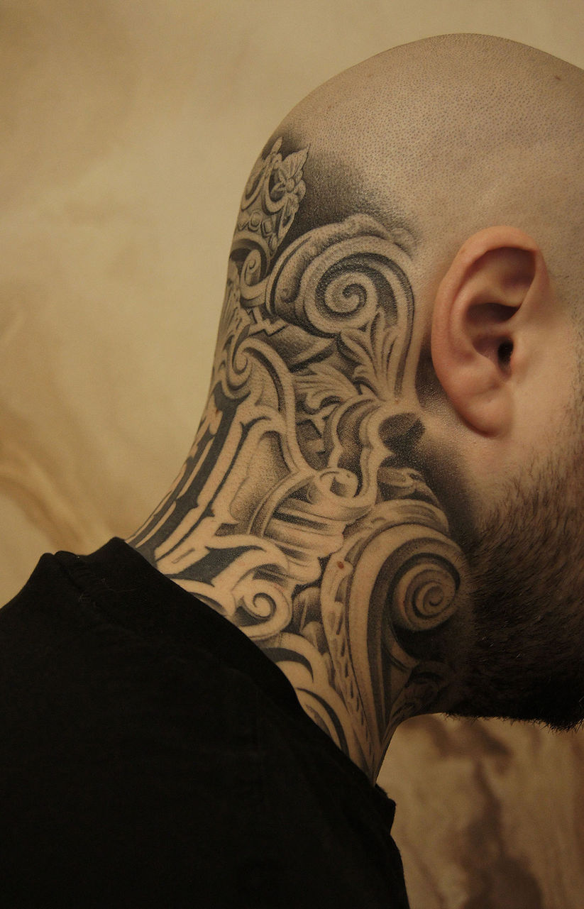 Tattoo im Nacken mit barockem Muster und geschwungenen Linien
Dekoratives Blackwork-Tattoo mit floralen Elementen