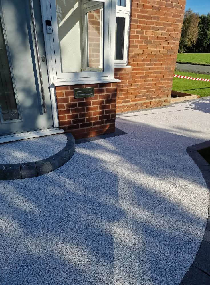 Silver grey resin bound path with charcoal edging by a front door