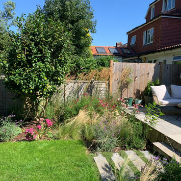 Side garden with gravel path and ornamental planting beside rendered wall.