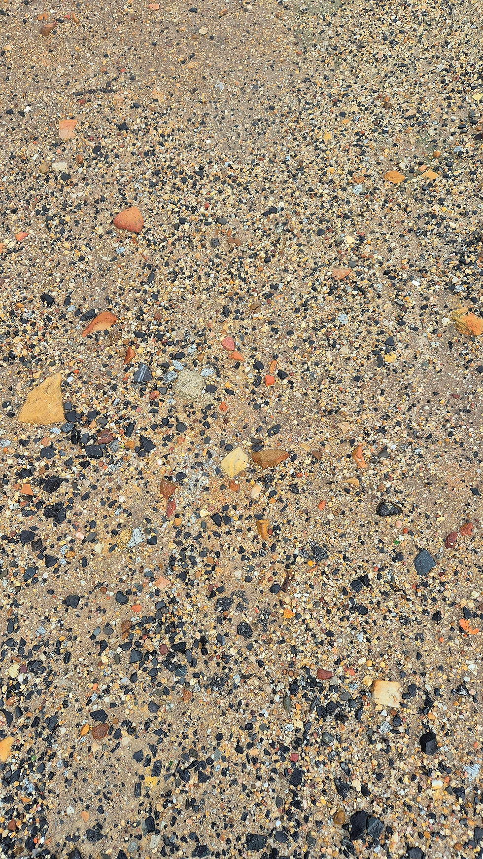 Exposed aggregate concrete surface with mixed coloured stones