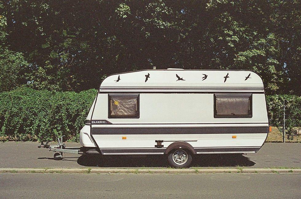Touring caravan parked on a hard surface in front of a hedge