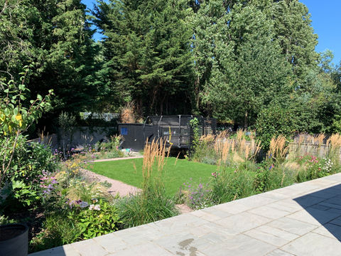 Wide open lawn with gravel path and planting in family-friendly garden.