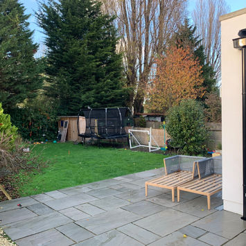 Rear garden before redesign with plain patio and lawn area.