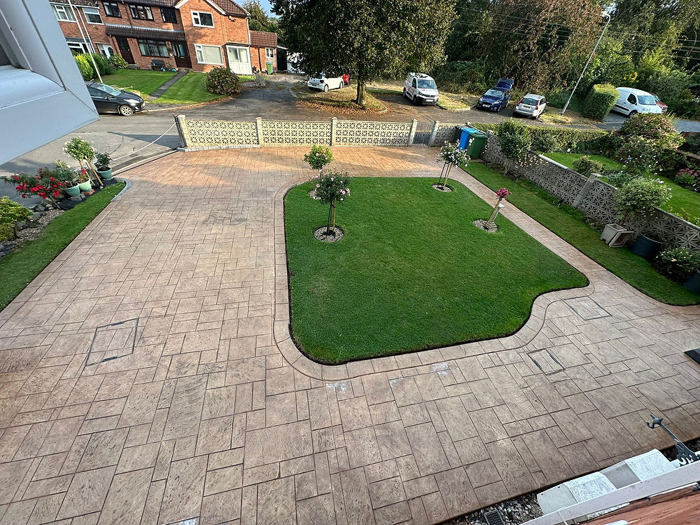 Buff imprinted concrete driveway wrapped around a shaped lawn with trees