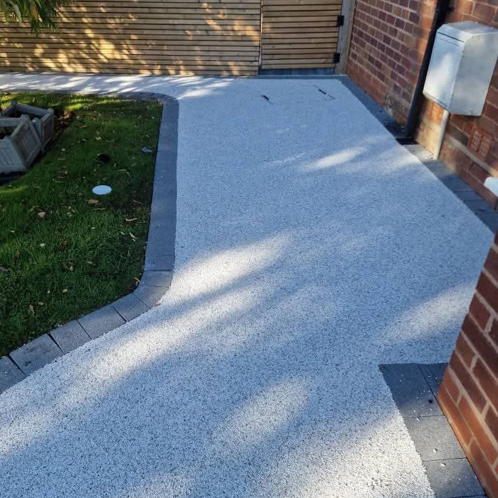 White resin bound pathway beside brick house and garden