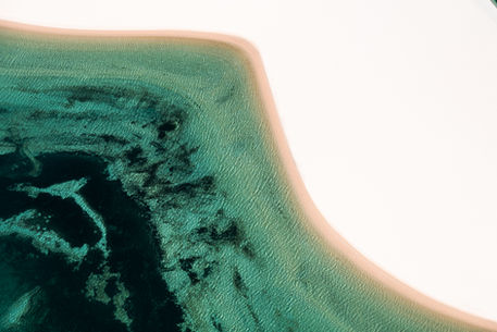 Fotografia aérea das dunas encontrando a lagoa, nos Lençóis maranhenses. Imagem com curvas e tons verde esmeralda. Abstrato natural. Fotografia de paisagem.