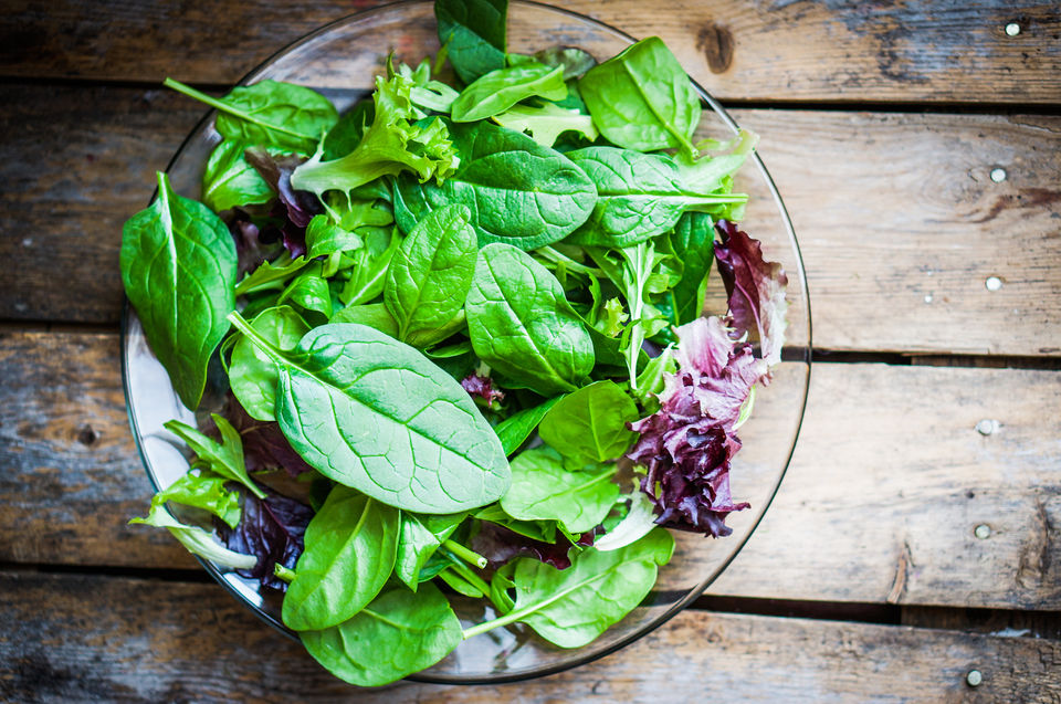 A glass bowl full of salad greens.