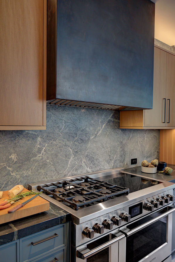 Metal cladding around kitchen hood by atelier bauherr.