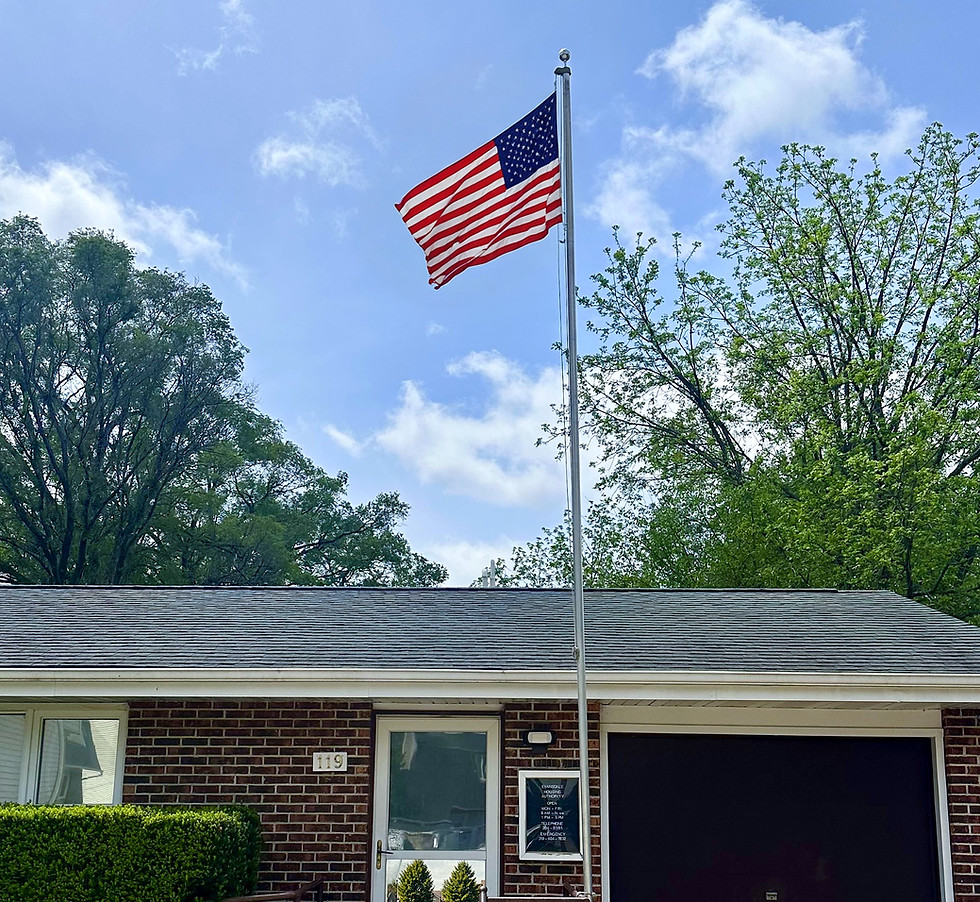 Photograph of the outside of the EMHA building, focused on the entrance and an American flag that is displayed out front of the building