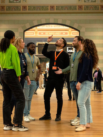 Visitors standing inside a grand Amsterdam museum gallery