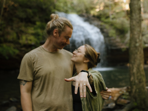 just engaged couple, girl holding out ring in front of waterfall