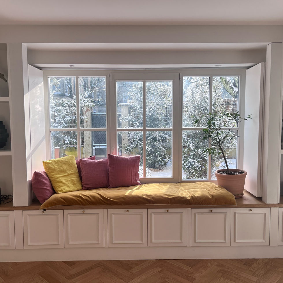 Un bow window élégant sublimé par un banc sur mesure avec assise en lin et coussins raffinés. La grande fenestration inonde l