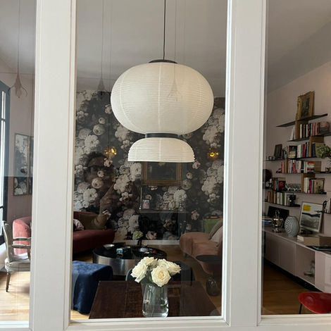 Salon au décor parisien avec papier peint fleuri, suspension wabi-sabi et mobilier coloré en velours.