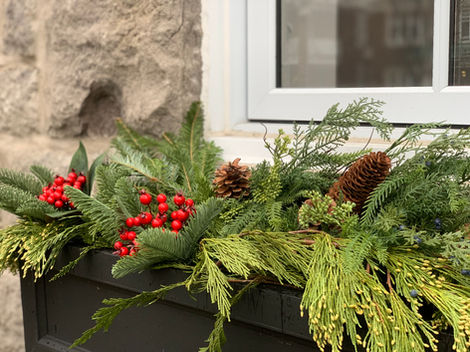 a window box filled with greenery and red berries