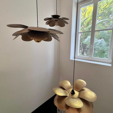 Une suspension dorée en forme de fleurs illumine l’escalier principal, apportant élégance, caractère et une touche sculptural