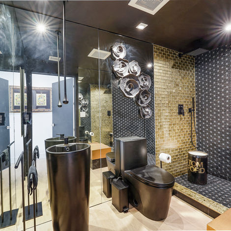 Une salle de bain moderne et audacieuse avec toilettes noires et accessoire Tom Ford.
