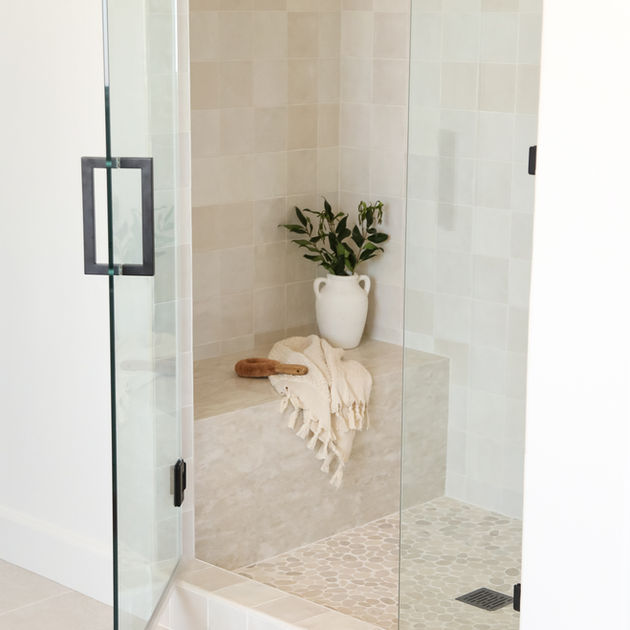 Modern spa-style bathroom with freestanding tub, dual vanities, black fixtures, oval mirrors, and natural wood cabinetry — Newport Beach interior design 