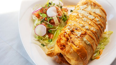 Large golden chimichanga with sauce, cheese crumbles, and a fresh radish salad.