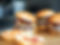 Delicious burgers with bacon, cheese and ketchup, ready to eat on wooden table.