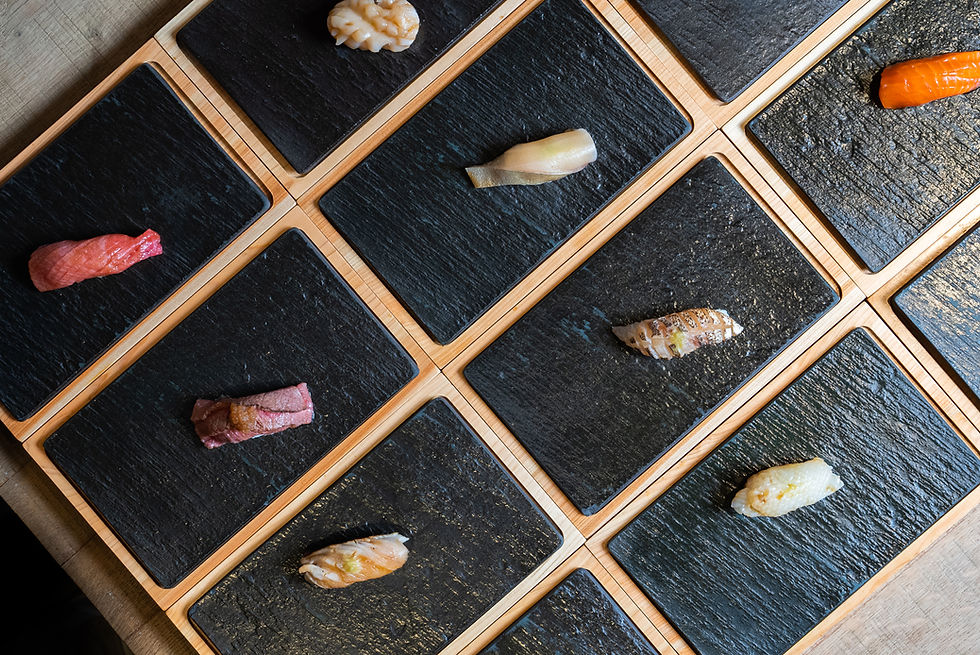 Assortment of sushi on individual black slate squares